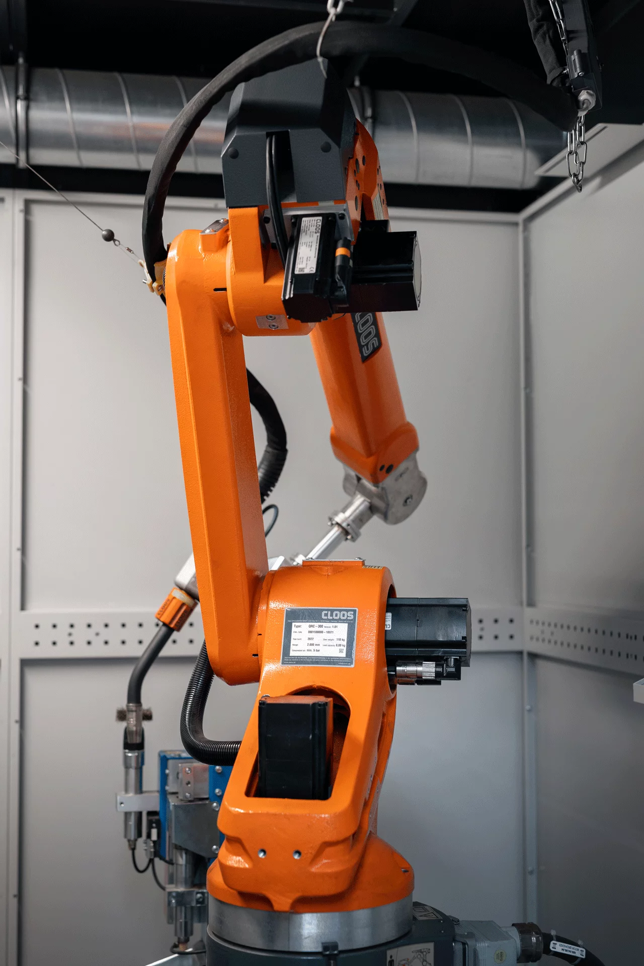 Ein knallorangener Schweißroboter in seiner Roboterzelle.