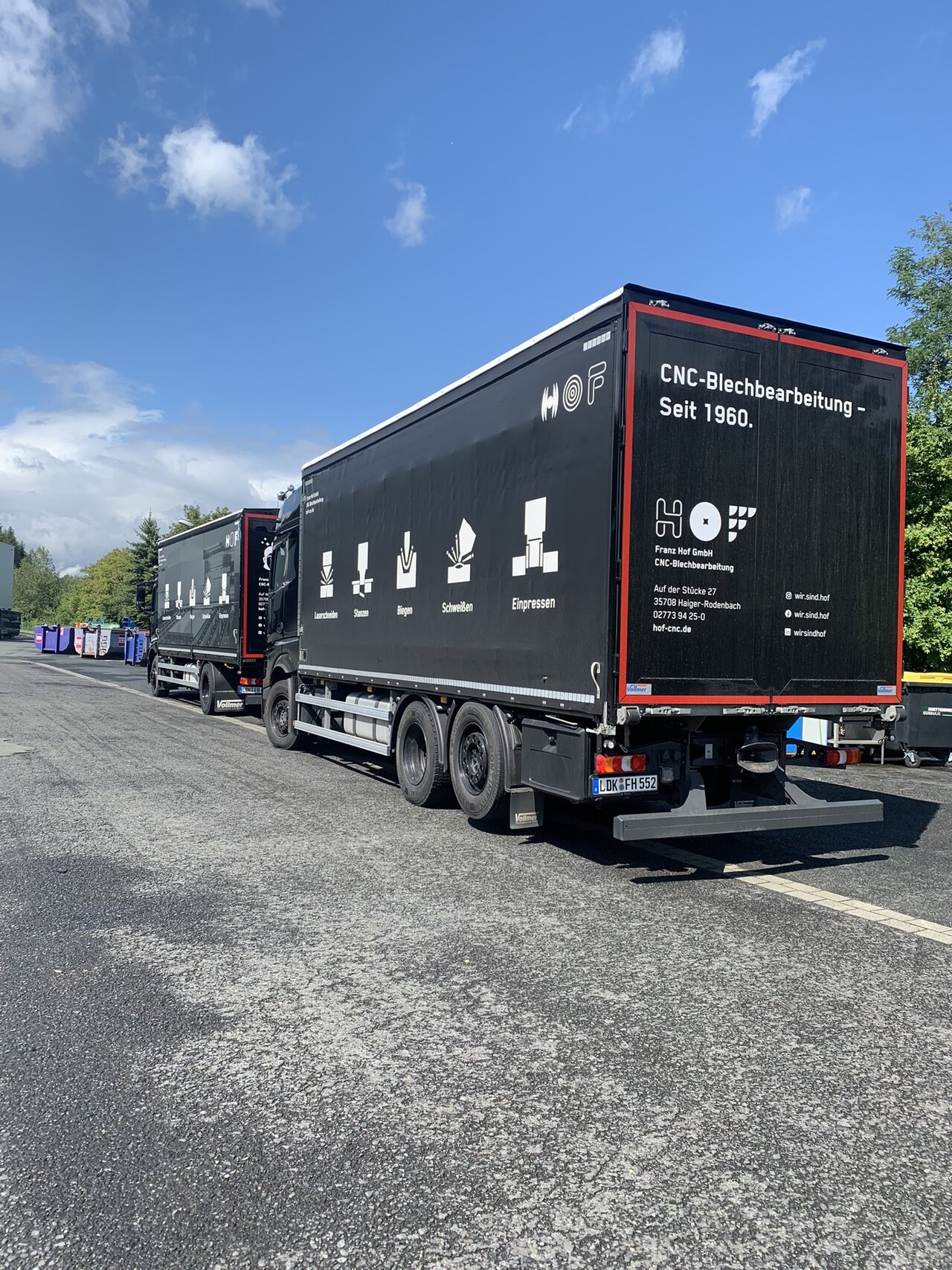 Zwei schwarze HOF-LKW von hinten, seitlich angeschnitten. Darauf zu sehen ist unser Corporate Design.