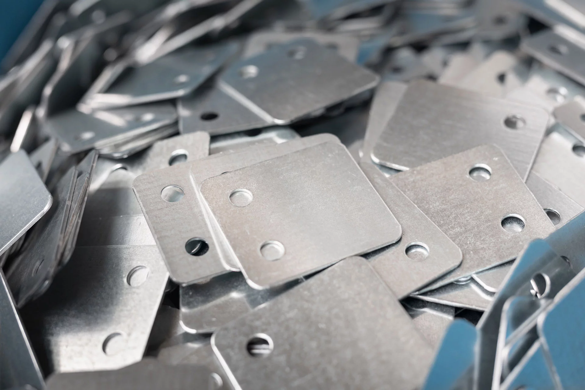 Viele kleine rechteckige Aluminiumbauteile mit Löchern und abgerundeten Kanten. 