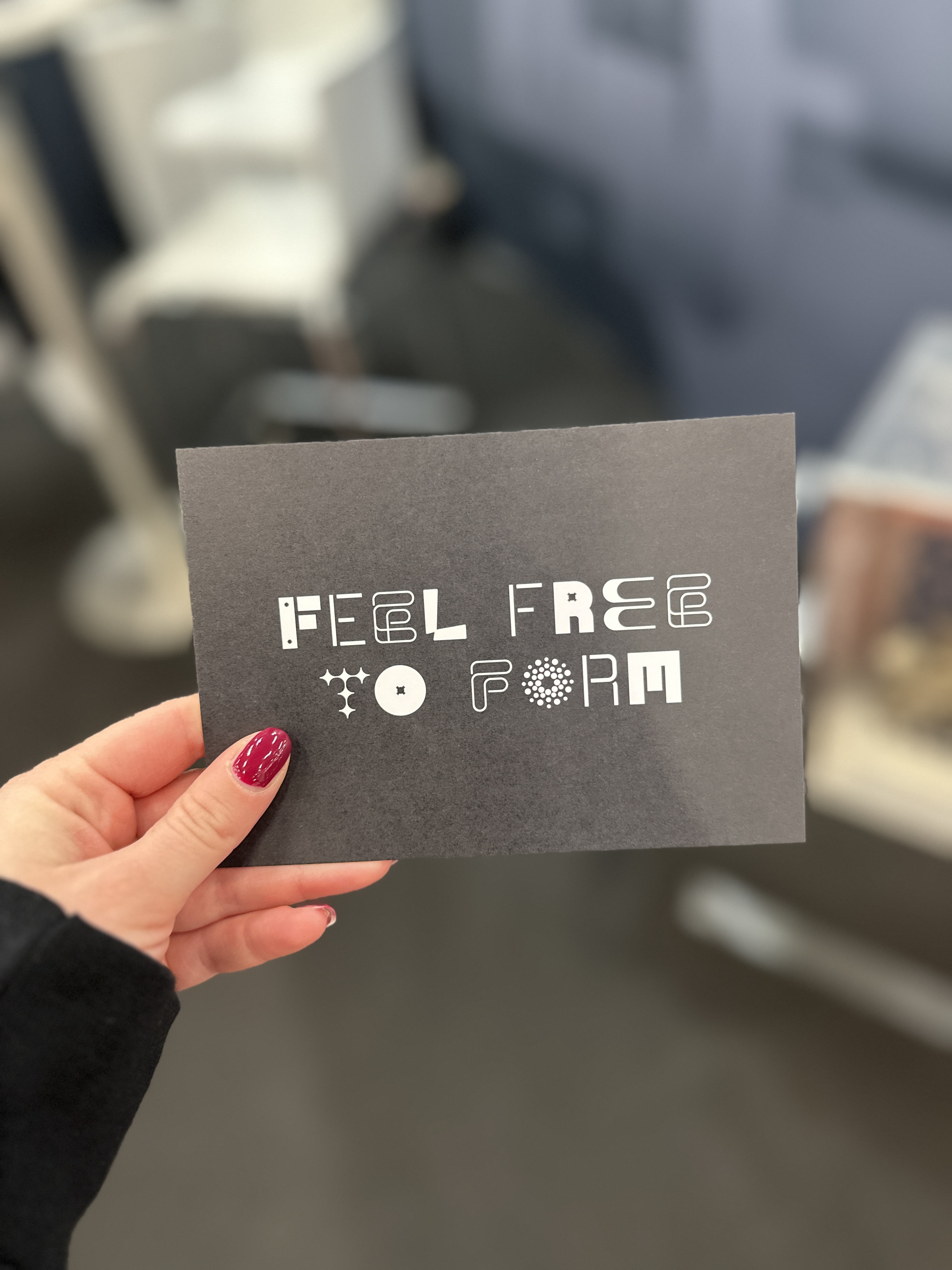 Jemand hält eine Karte von uns mit dem Schriftzug "FEEL FREE TO FORM" hoch.