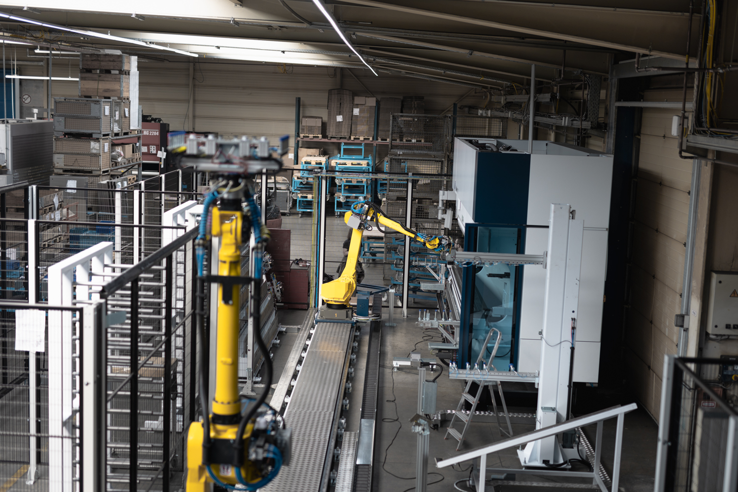 Ein Blick in die Fertigung aus Vogelperspektive. Zu sehen ist ein gelber Roboter an einer Kantmaschine von TRUMPF.